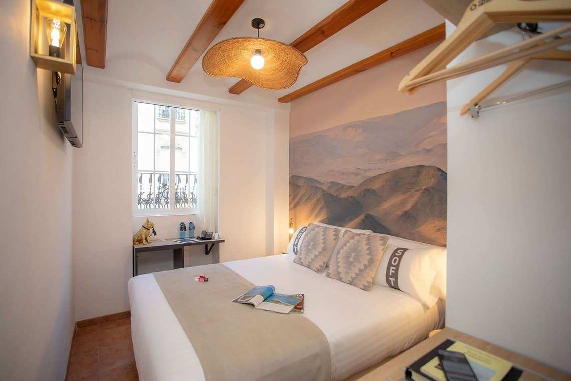 Gemütliches Schlafzimmer im Casual Natura Valencia: Bett mit Bergmotiv-Wand & Naturholz.