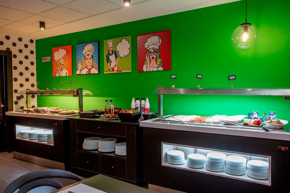 a buffet line in a restaurant with a green wall