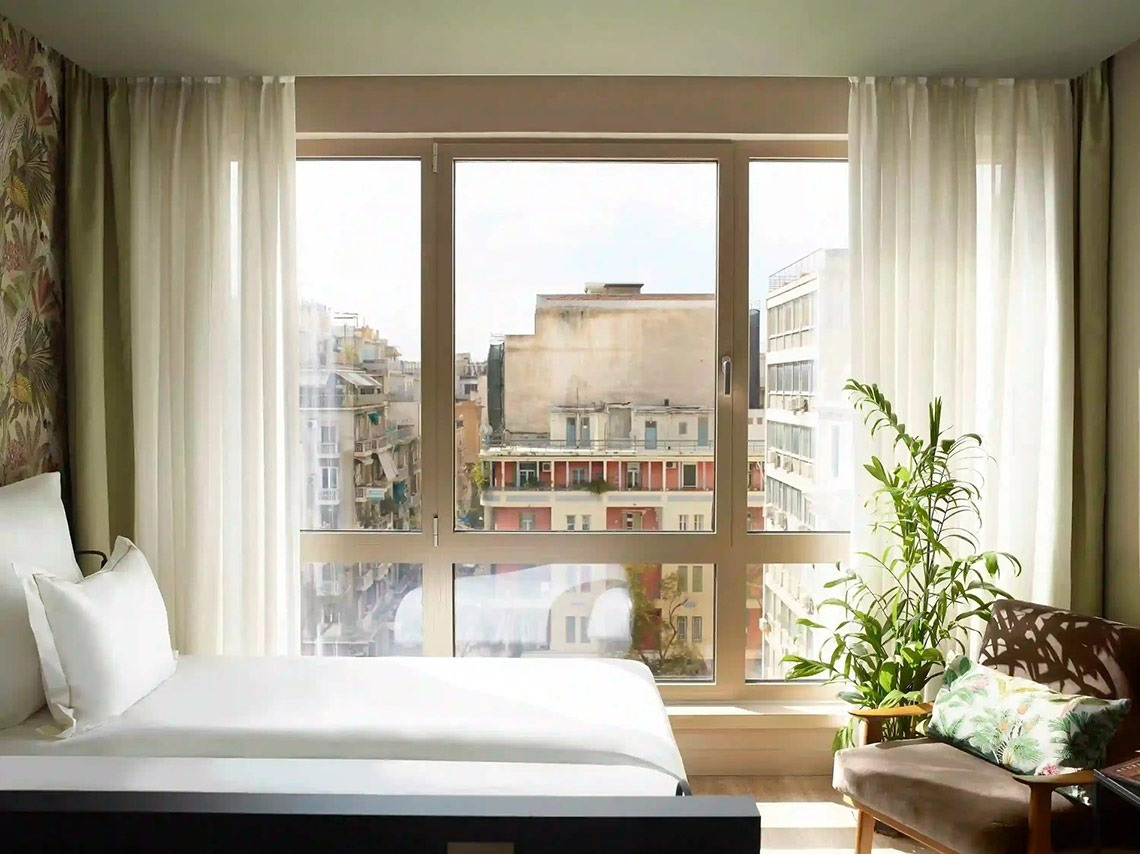 una habitación con una cama y una ventana con vistas a la ciudad