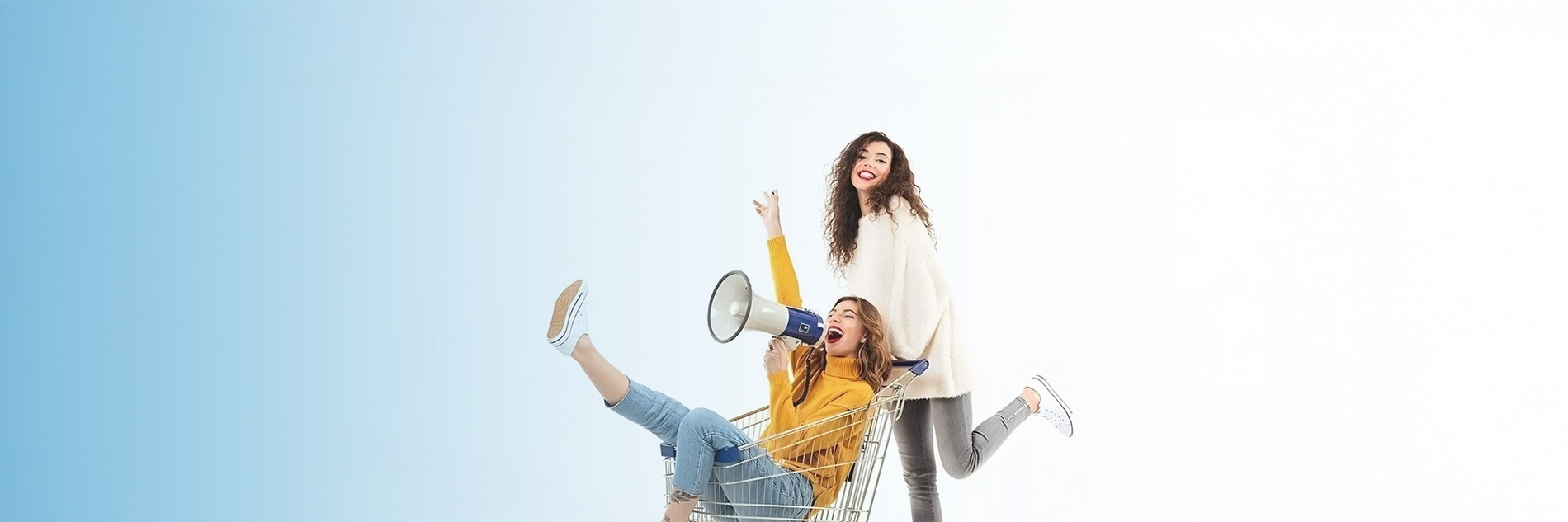 una mujer sostiene un megáfono mientras una mujer se sienta en un carrito de compras