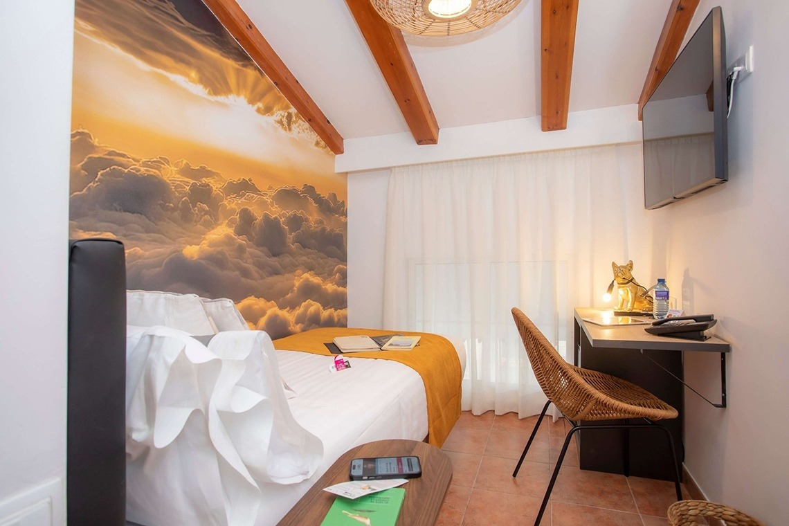 Gemütliches Hotelzimmer im Casual Natura Valencia mit Wolkenmotiv-Wand und Holzbalken. Ideal für entspannten Aufenthalt.