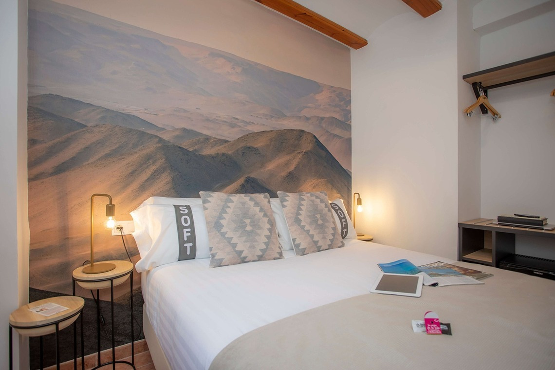 Gemütliches Schlafzimmer im Casual Natura Valencia mit Bergwand-Tapete, Doppelbett & Nachttischen.