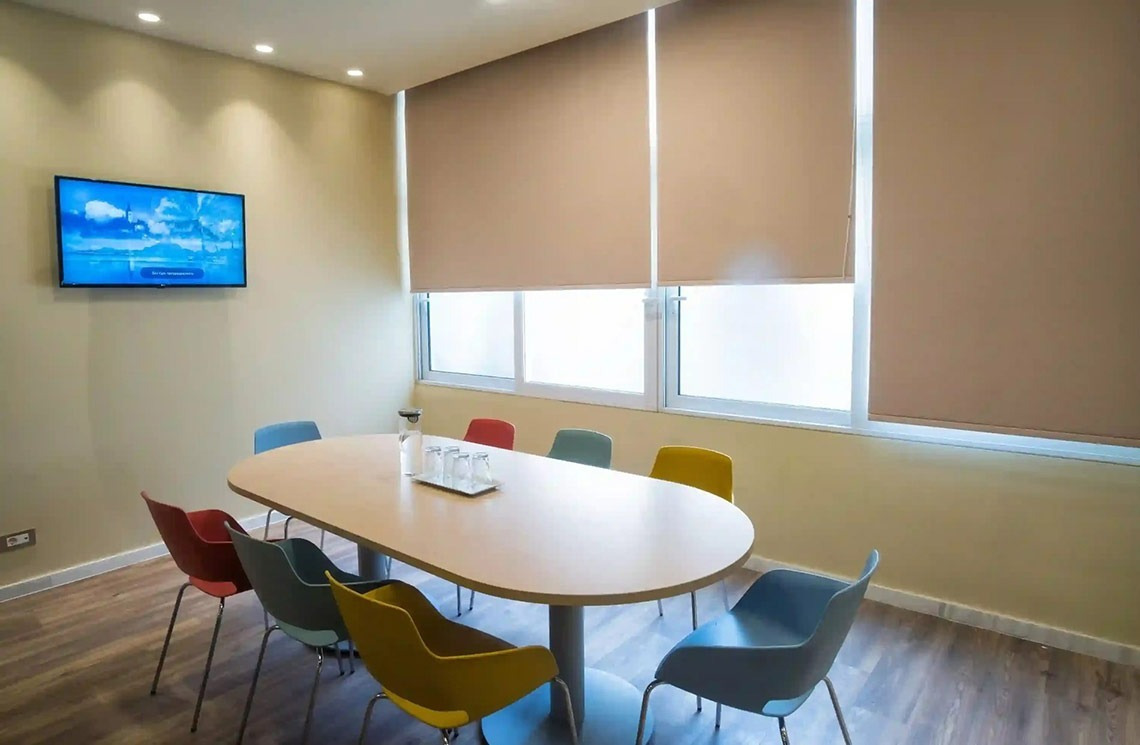 una sala de conferencias con una mesa ovalada y sillas de colores