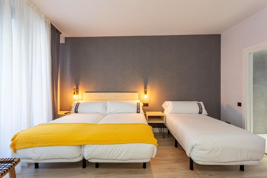 una habitación de hotel con tres camas y una pared gris