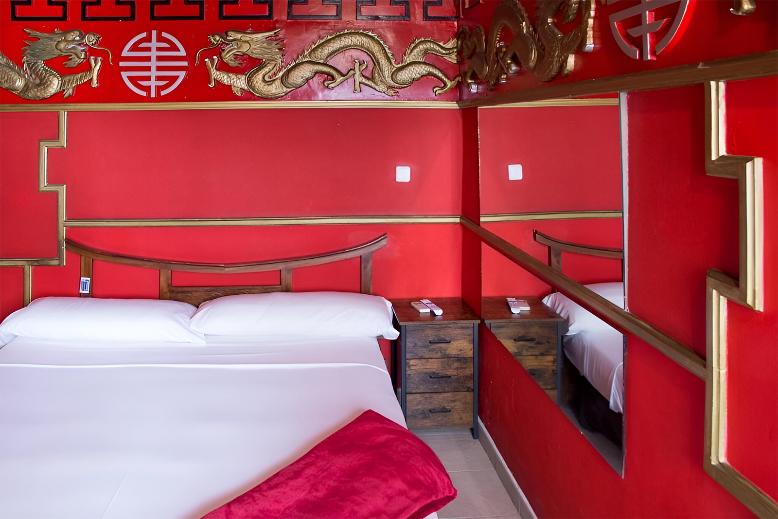 Gemütliches Zimmer im Casual de las Civilizaciones, Valencia, mit roten Wänden, Drachenmotiven und einem Doppelbett. Günstiges Hotel.