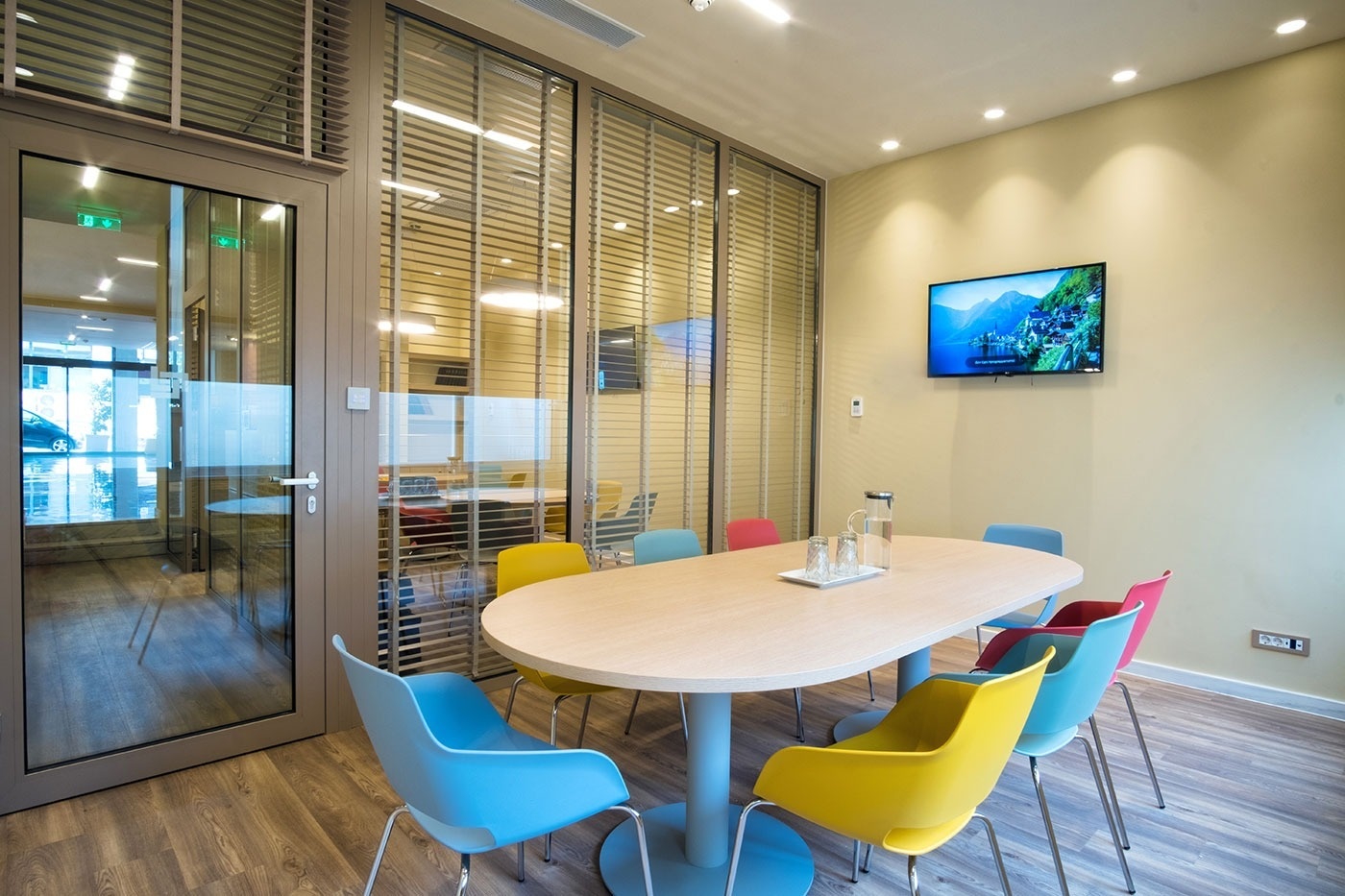 een vergaderruimte met een ovale tafel en kleurrijke stoelen