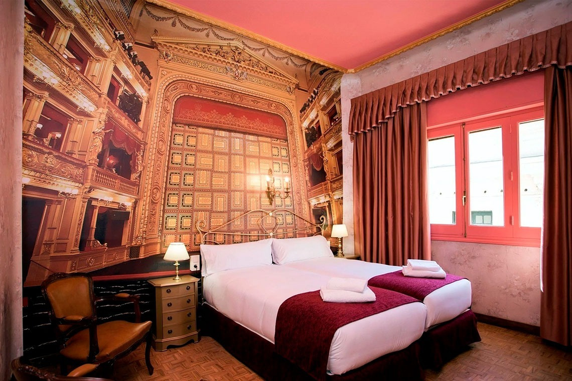 a bedroom with two beds and a picture of a theatre on the wall