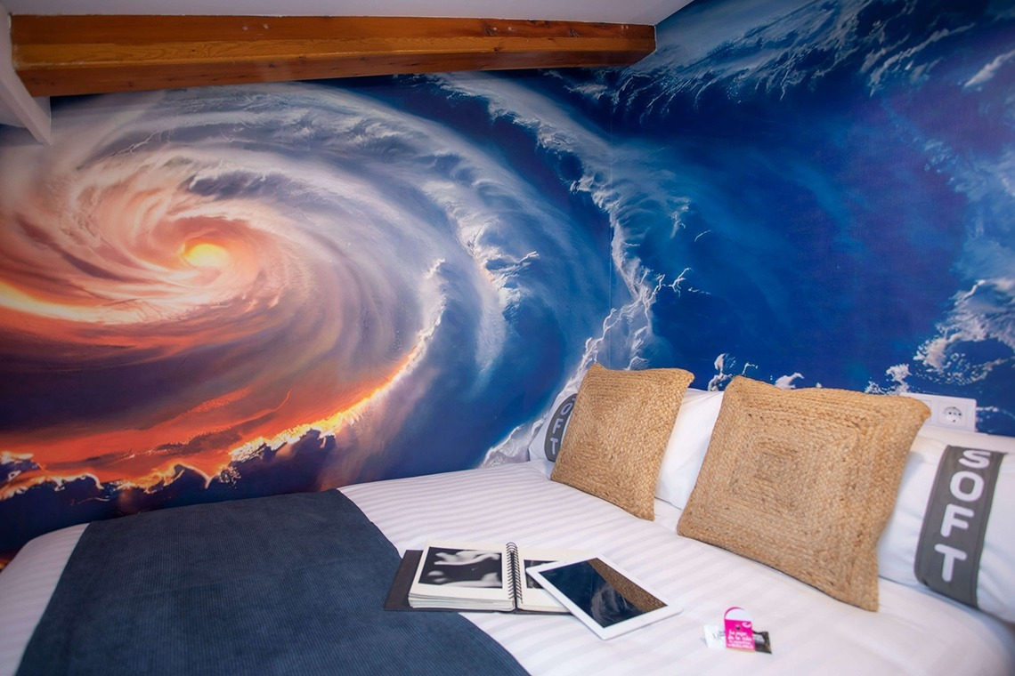 Ein detailreiches Wandgemälde eines Sturms über dem Bett im Casual Natura Valencia - Von der Natur inspiriertes Hotel.