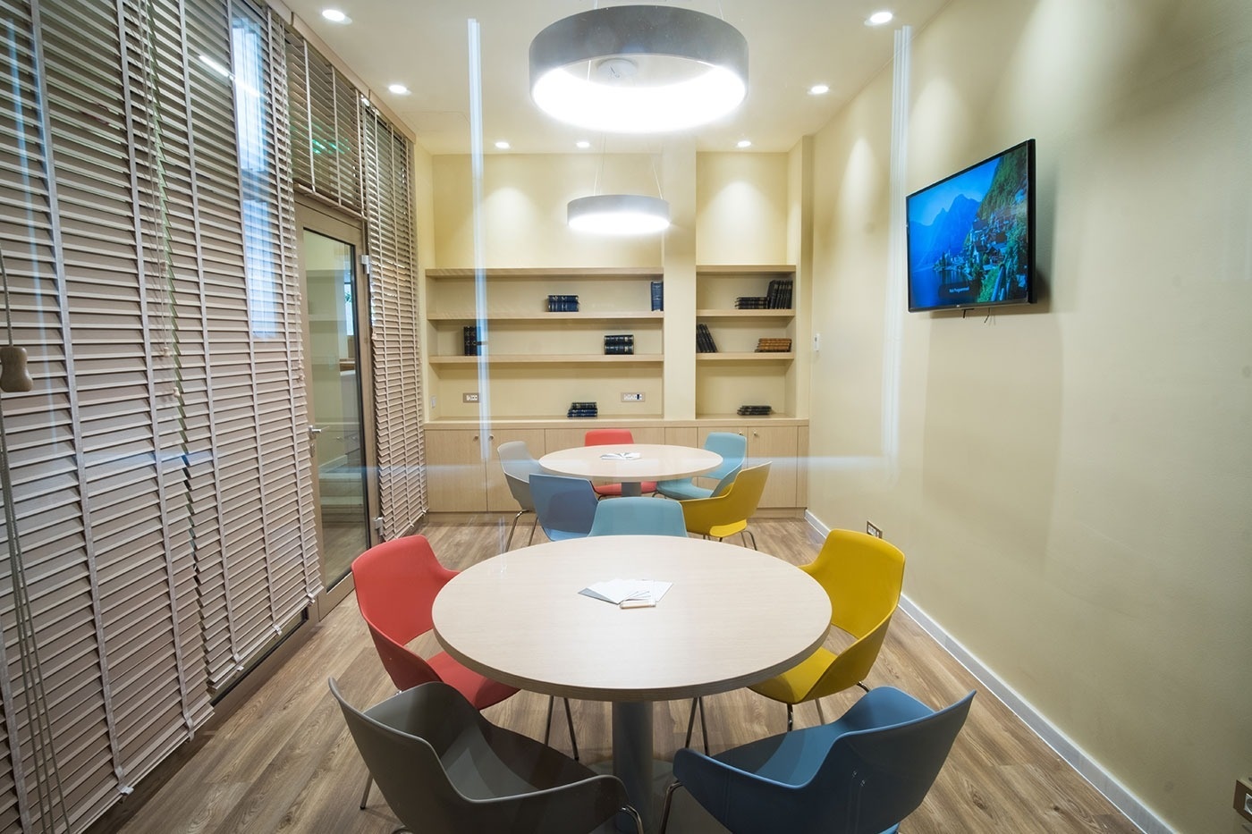 een kamer met een ronde tafel en kleurrijke stoelen