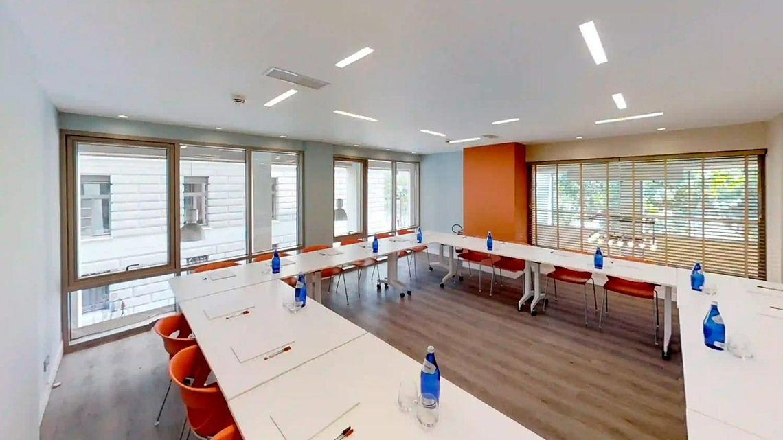 una sala de conferencias con mesas y sillas y botellas de agua