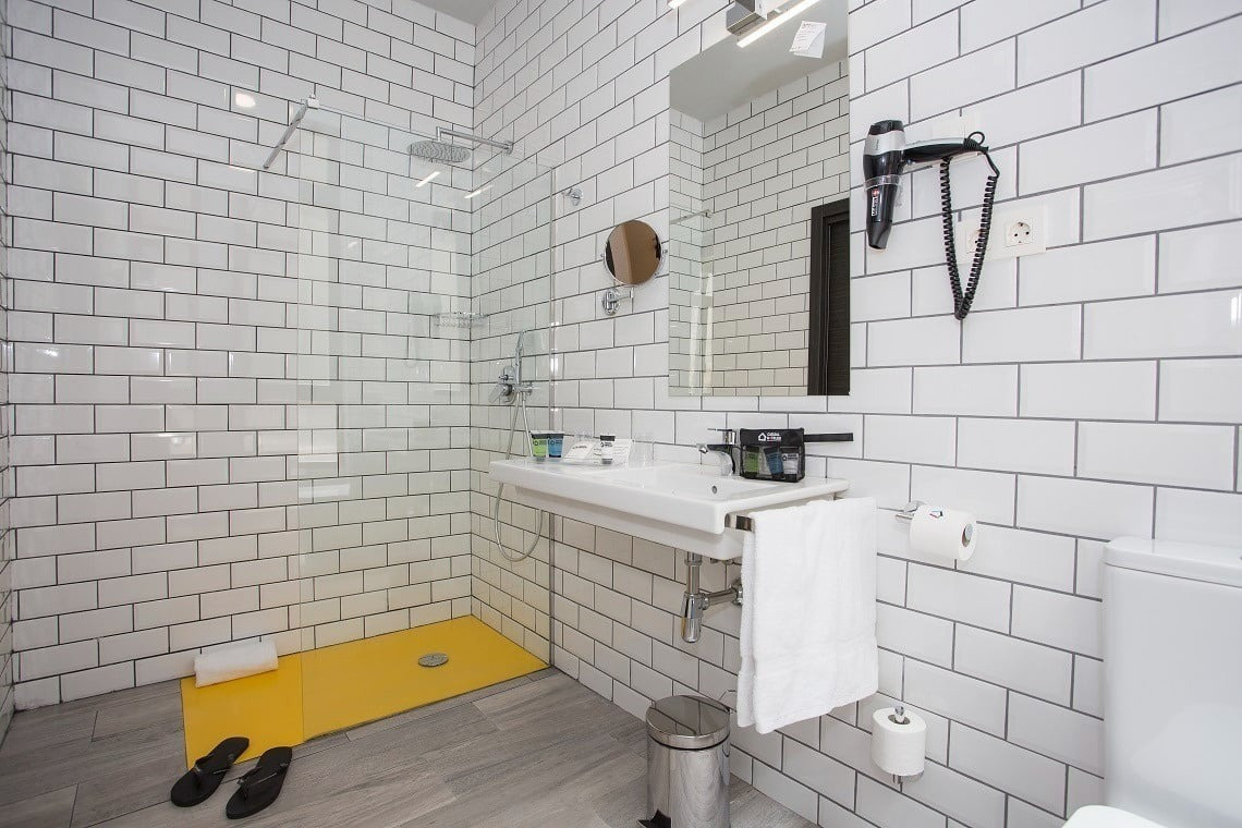 a bathroom with white tiles and a yellow walk in shower