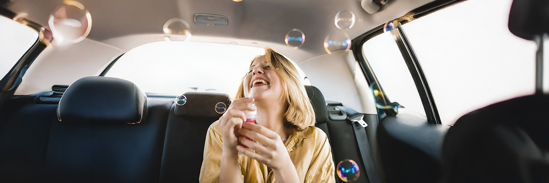 dos mujeres se divierten en el asiento trasero de un coche soplando burbujas de jabón