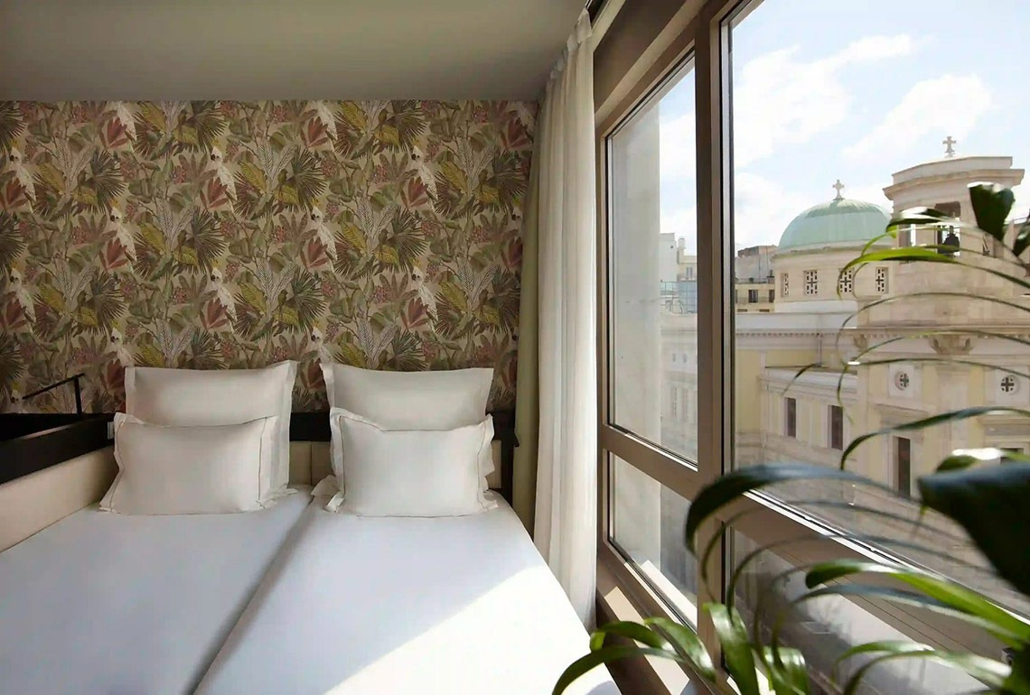 una habitación con una cama y una ventana con vista a un edificio