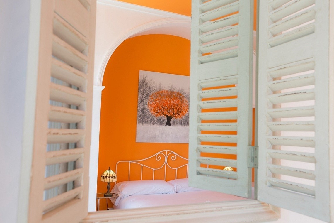 a bedroom with orange walls and white shutters