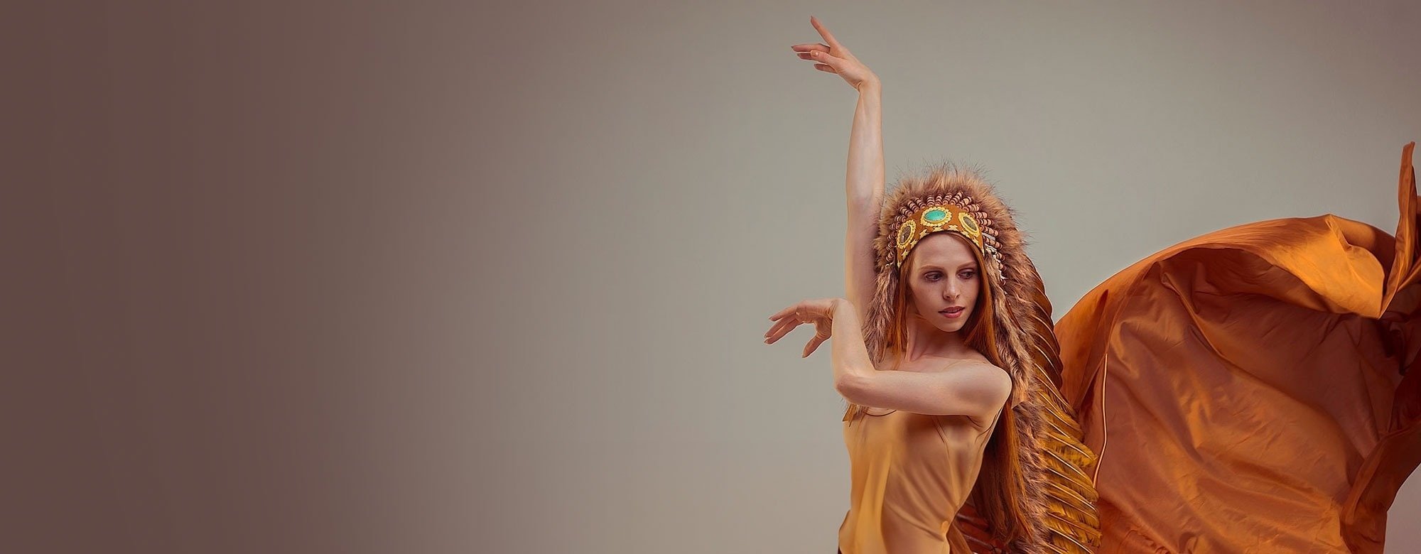 een vrouw draagt een hoofdtooi met veren en een oranje jurk