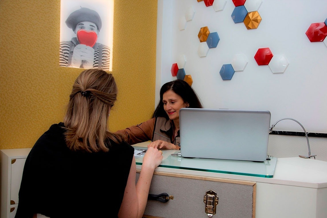 a woman sits at a desk with a laptop in front of her