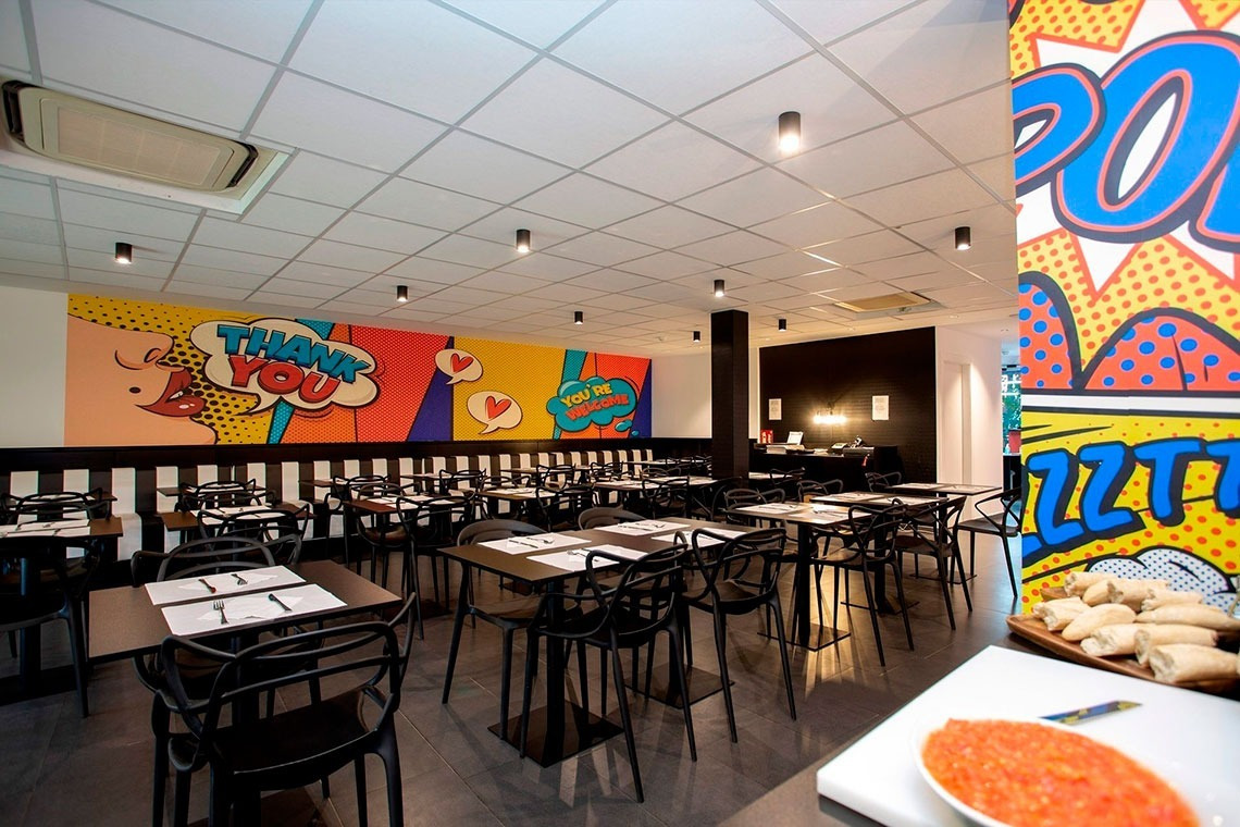 a restaurant with tables and chairs and a mural that says thank you