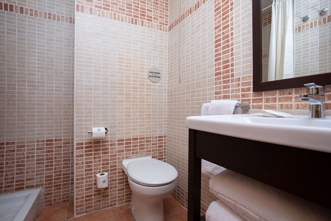 Badezimmer im Casual Natura Valencia: Toilette, Waschbecken & Spiegel mit Naturtönen.