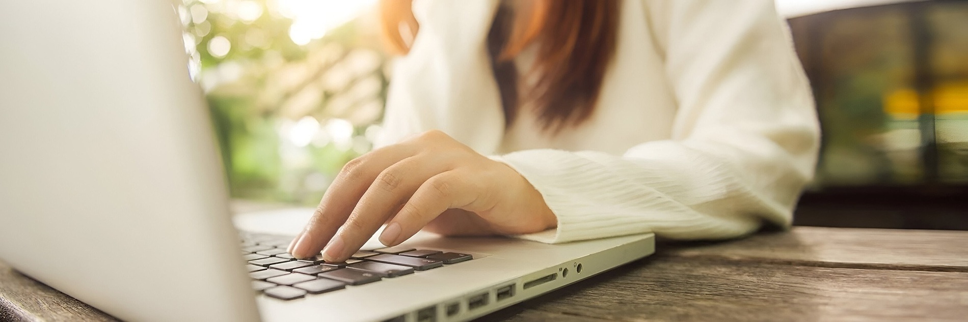 una donna sta digitando su un computer portatile su un tavolo di legno