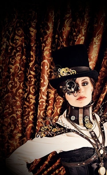 una mujer con un sombrero de copa y gafas de sol está frente a una cortina marrón