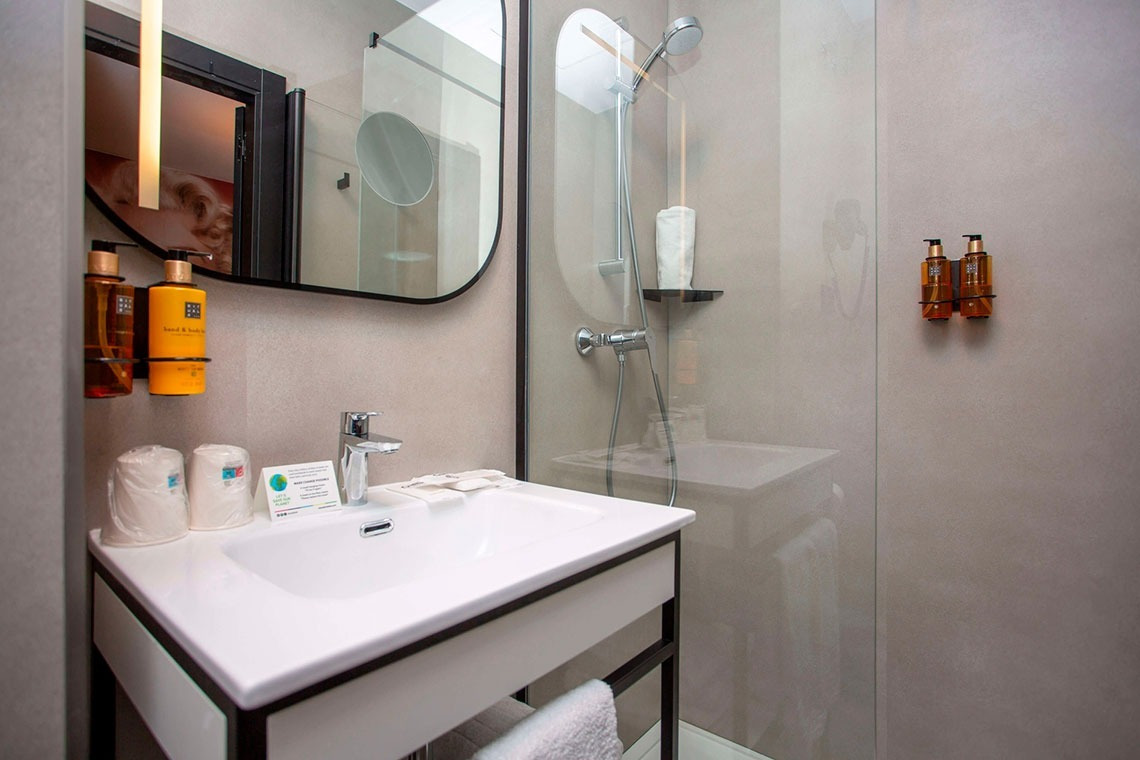 a bathroom with a sink and two bottles of rituals hanging on the wall