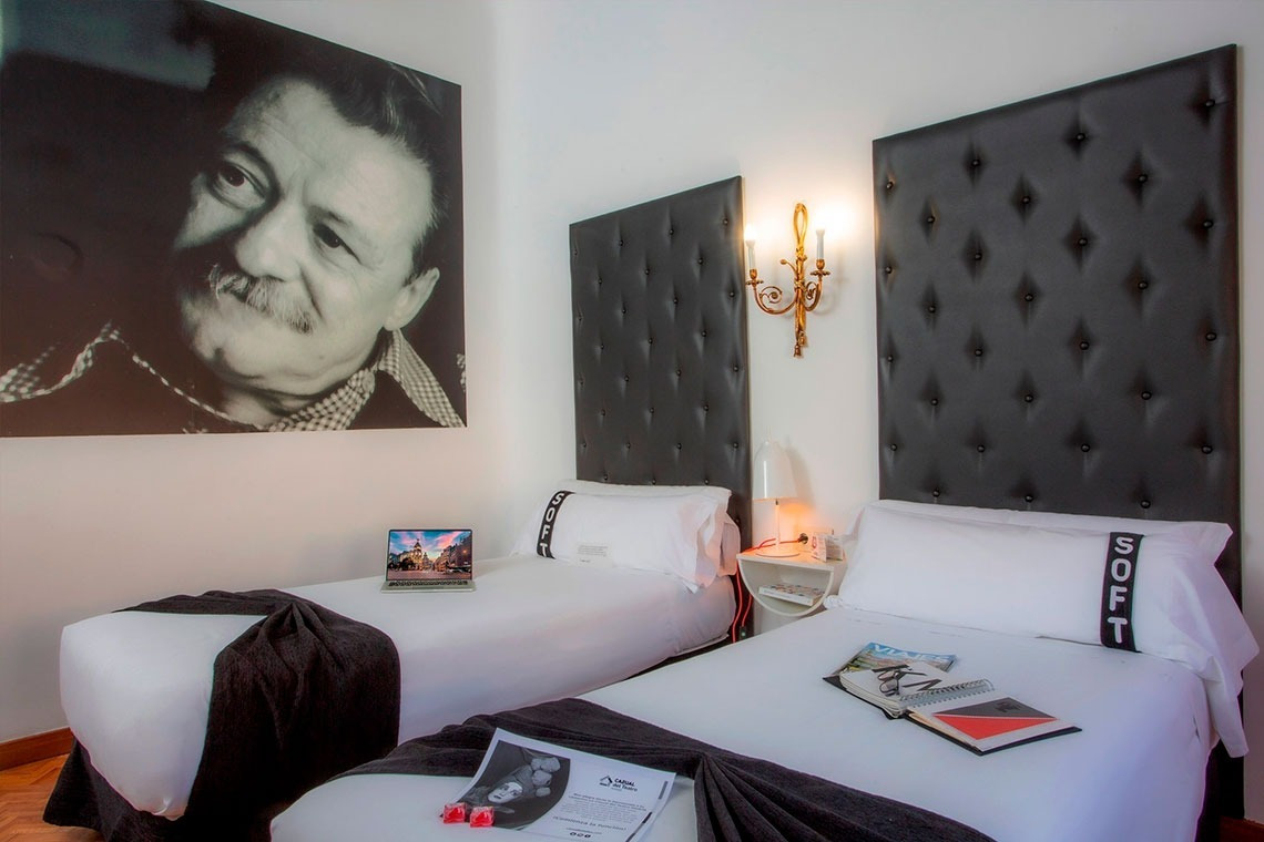 a bedroom with two beds and a picture of a man on the wall
