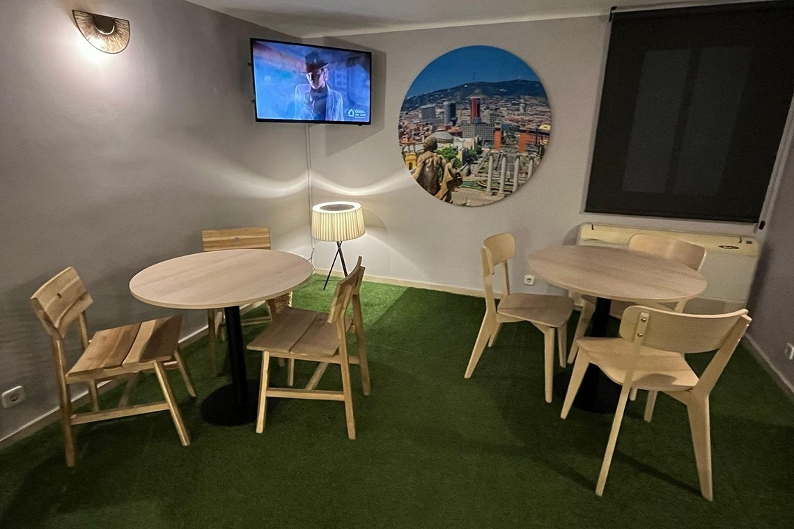 una habitación con mesas y sillas y una televisión en la pared