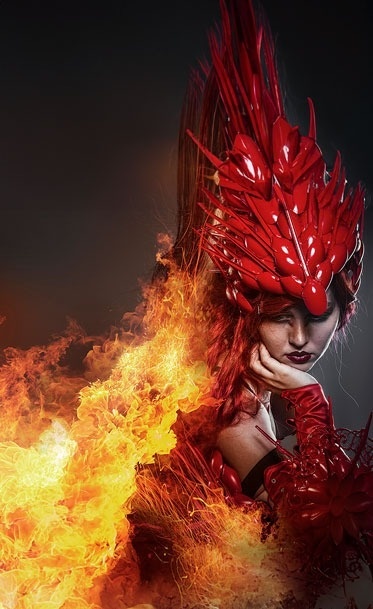 una mujer con un disfraz rojo está rodeada de llamas .