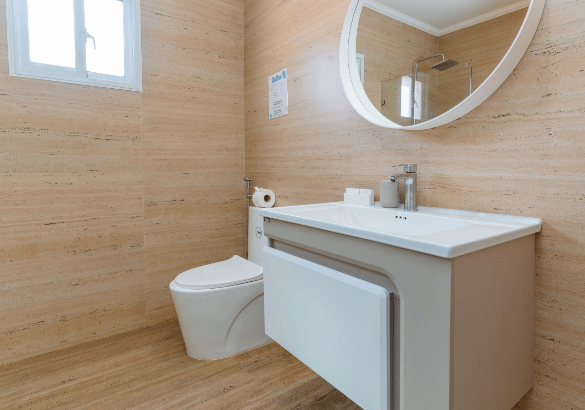 Baño moderno con inodoro y lavabo, espejo redondo y ducha visible. Casual: Eden Bayahibe