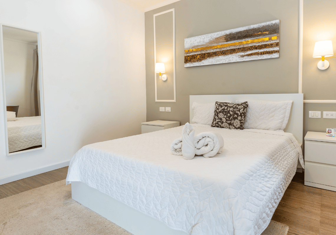 Cama limpia y blanca en hotel. Casual: Eden Bayahibe. Arte moderno en pared.