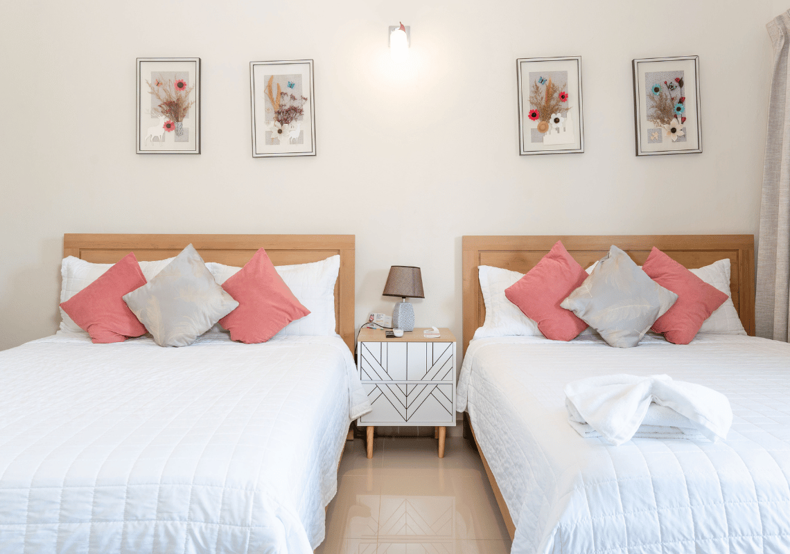 Dormitorio de hotel con dos camas individuales, ropa de cama blanca y arte floral. Casual: Eden Bayahibe