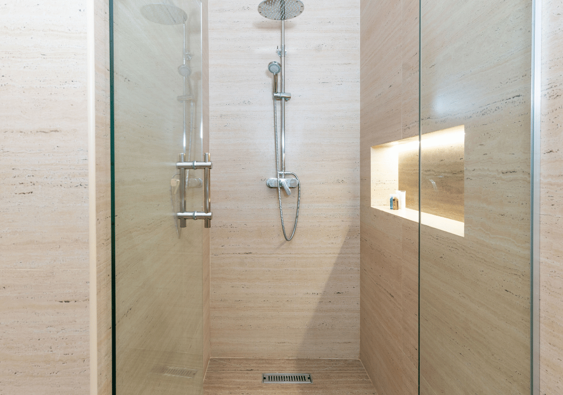 Ducha moderna con pared de mármol claro, cabezal de ducha y nicho iluminado. Casual: Eden Bayahibe