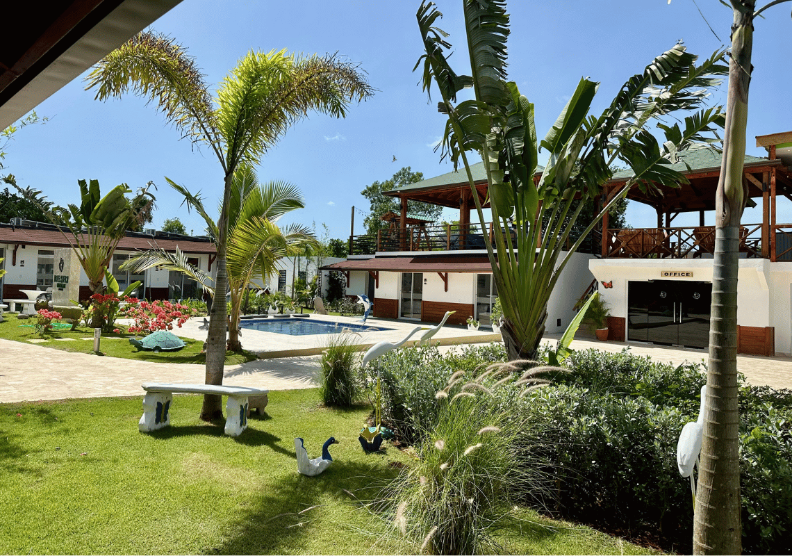 Casual: Green Village Bayahibe: Piscine et jardin luxuriant dans un complexe tropical avec une signalisation d'Casual: Green Village Bayahibe.