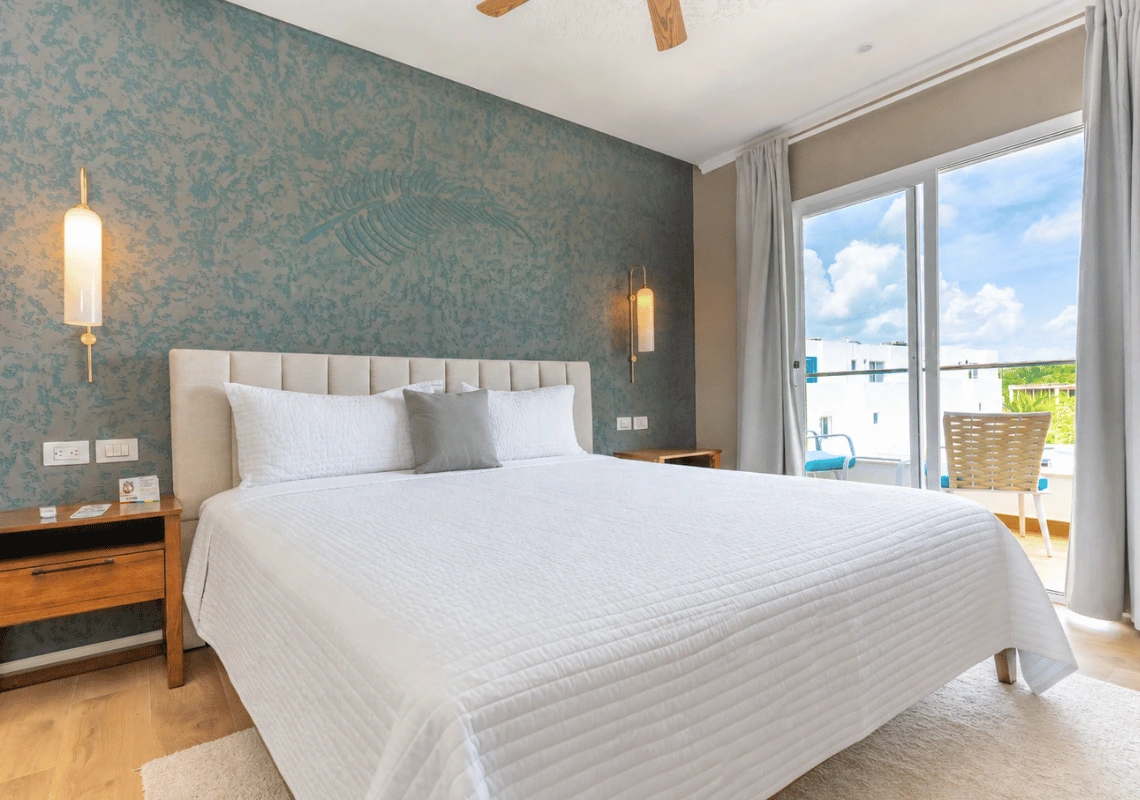 Dormitorio elegante con cama blanca, pared decorada y balcón con vistas. Casual: Green Village Bayahibe