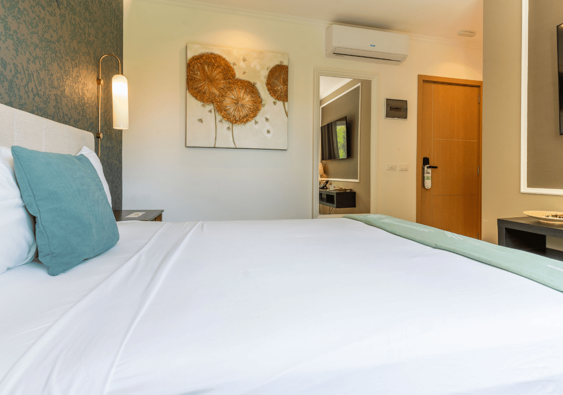 Cama doble con almohadas turquesas y arte de diente de león en una Casual: Green Village Bayahibe.
