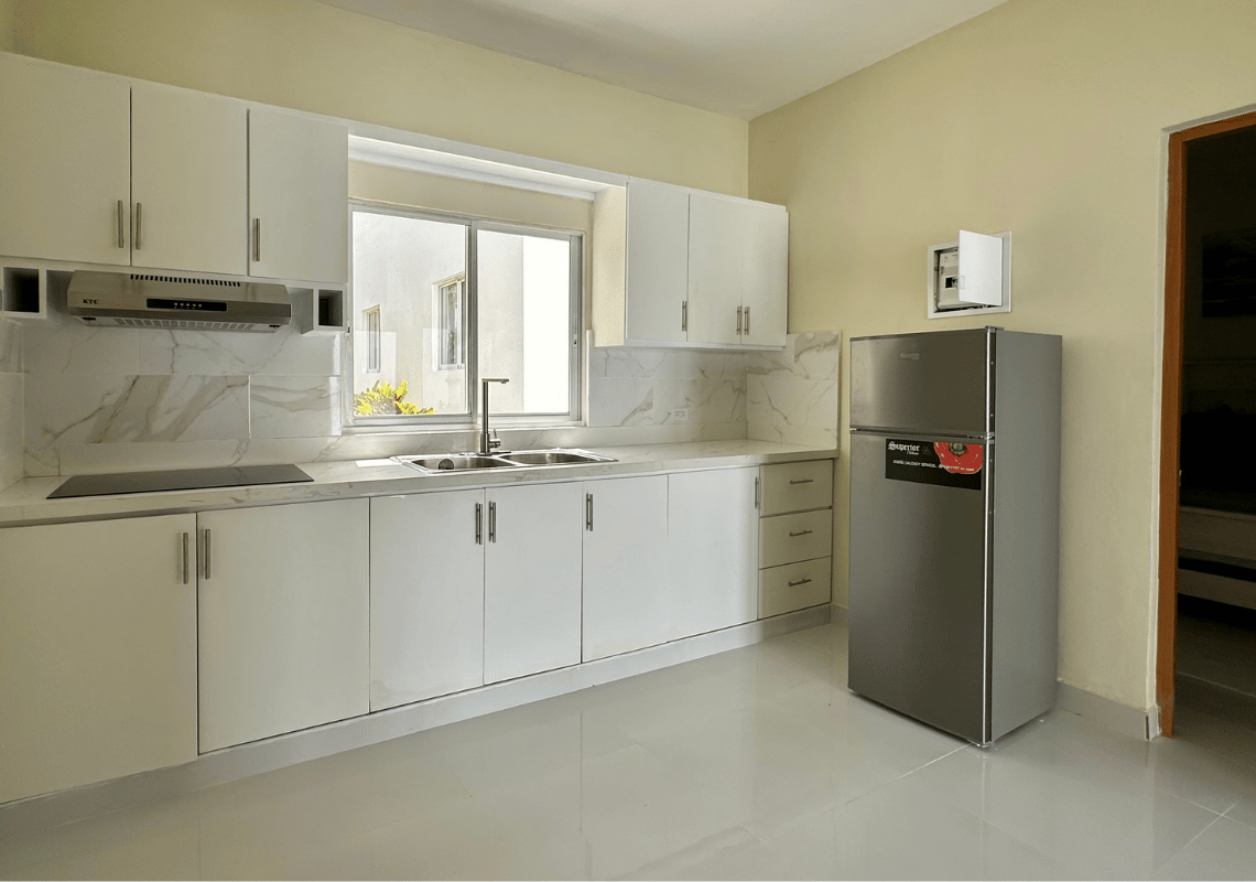 Cuisine moderne et fonctionnelle avec placards blancs, évier, plaque de cuisson et réfrigérateur pour votre séjour Casual: Green Village Bayahibe.
