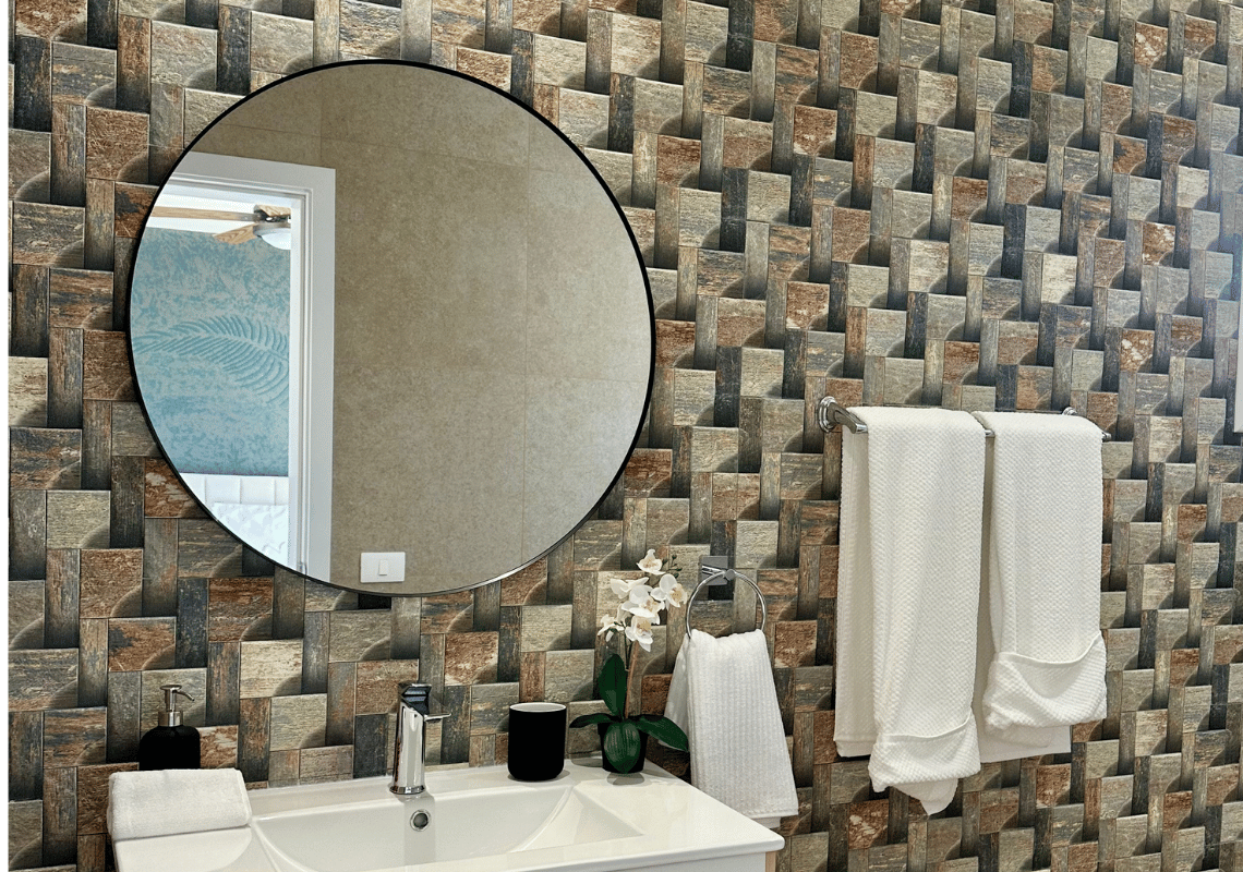 Salle de bain moderne avec miroir rond, serviettes blanches sur porte-serviettes et mur texturé au motif 3D. Casual: Green Village Bayahibe