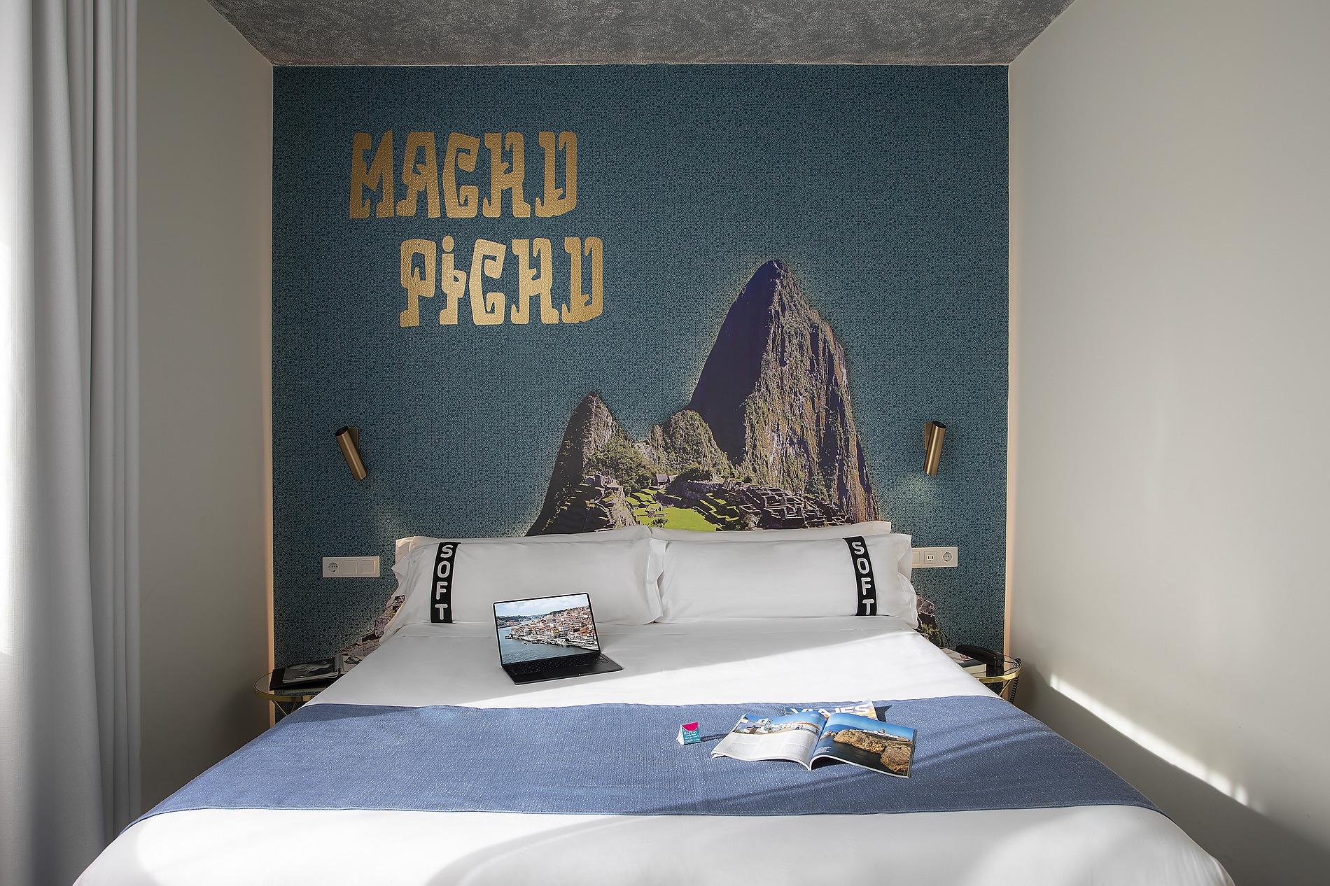 Cama con decoración de Machu Picchu y laptop abierta, ideal para Casual: Inca Porto.