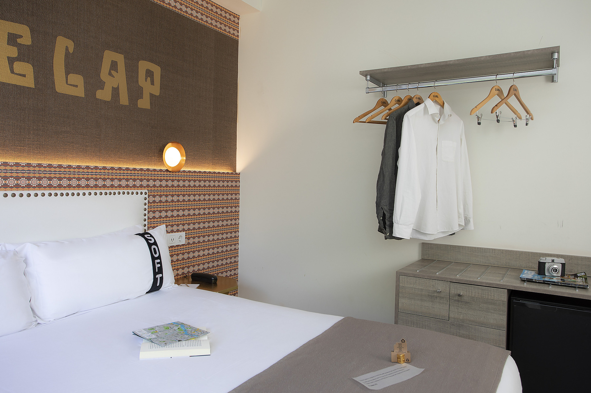 Habitación de hotel moderna con perchero, cama y detalles de diseño en la pared. Casual: Inca Porto