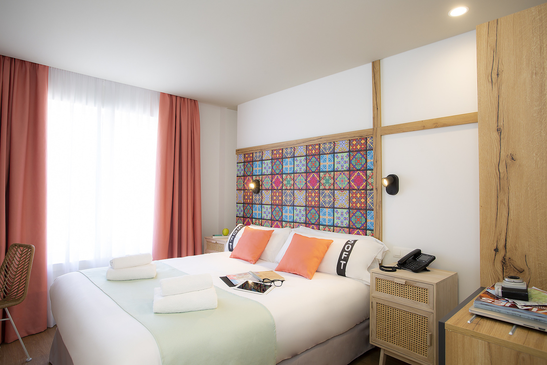 Cama de matrimonio con cabecero colorido y mesita de noche de madera en una habitación de hotel, ideal para tu Casual: Raizes Porto.
