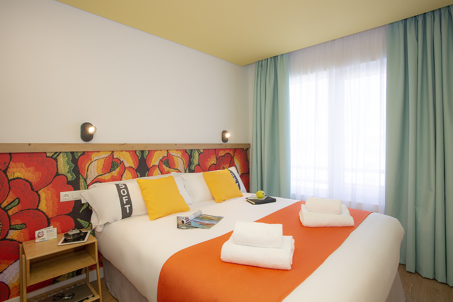 Habitación de hotel cómoda con cama extragrande, almohadas y manta naranja. Casual: Raizes Porto.