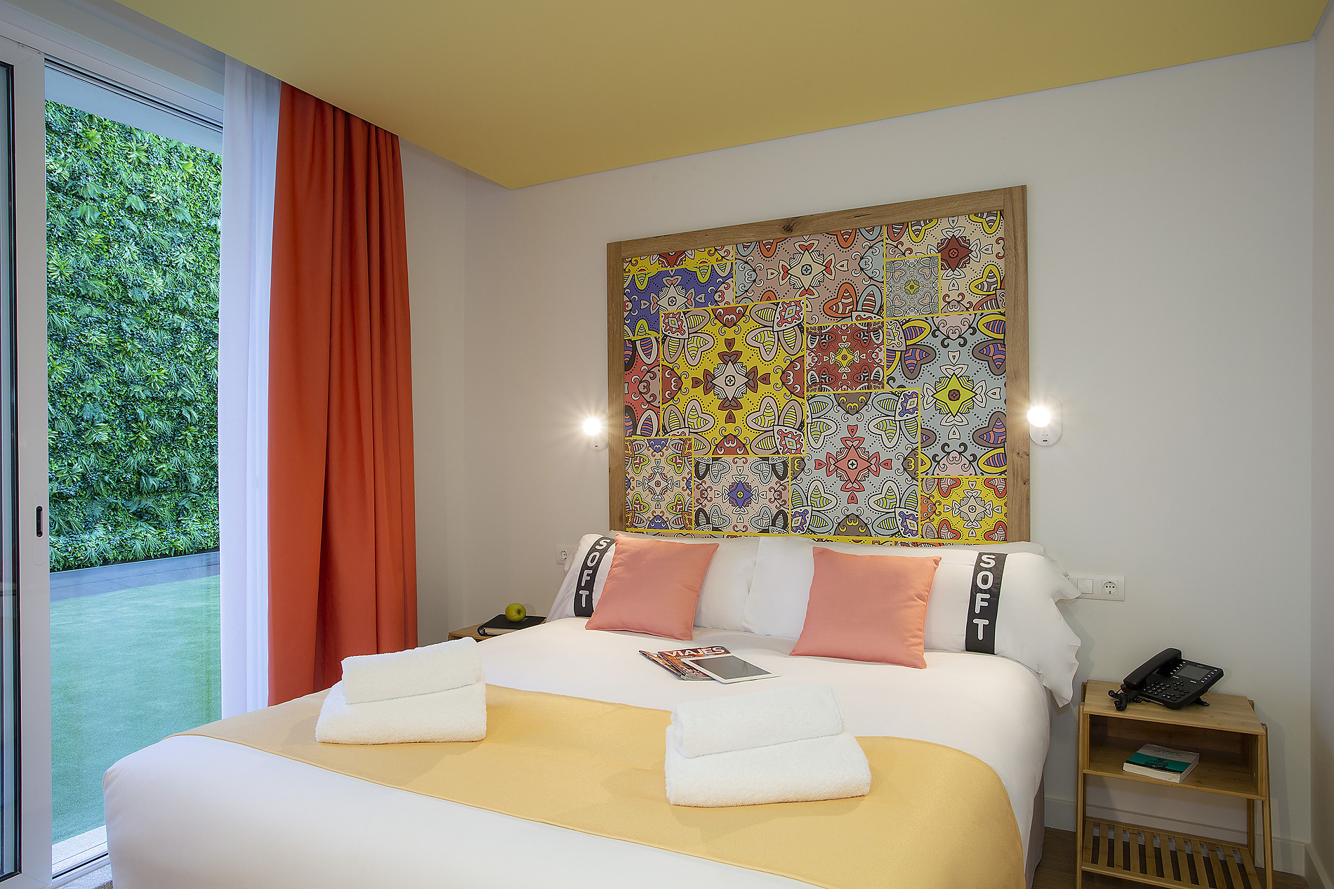 Habitación moderna con cama confortable, almohadas color coral yCasual: Raizes Porto. Vista a jardín vertical.
