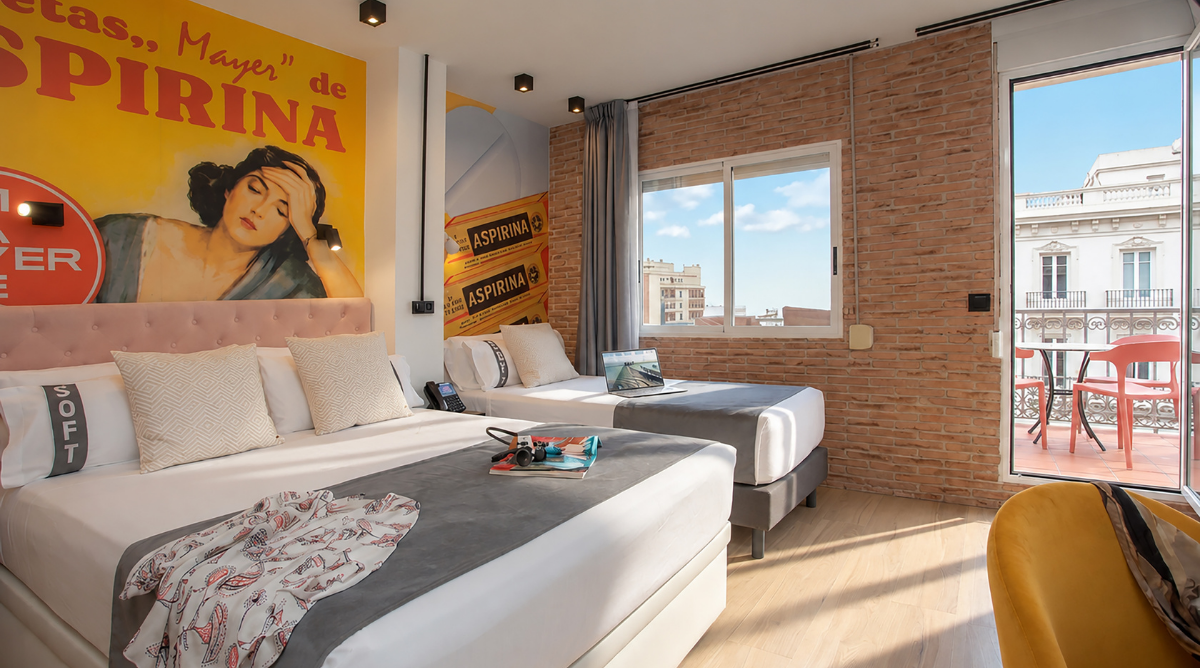 Doble cama y cama individual en habitación con mural retro y balcón con sillas naranjas. Casual Vintage