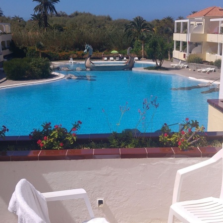 una silla blanca se sienta frente a una gran piscina