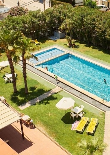 una vista aérea de una piscina rodeada de palmeras y mesas y sillas .