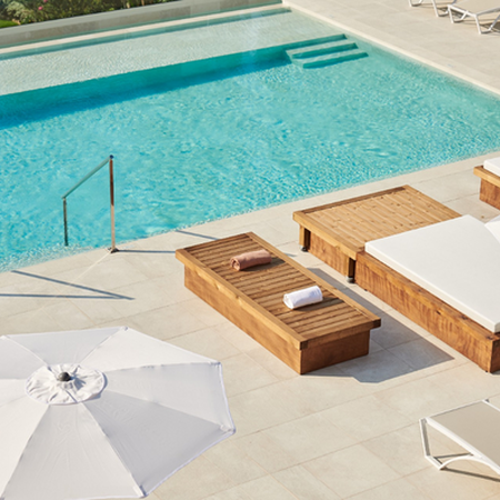 una piscina rodeada de muebles de madera y sombrillas