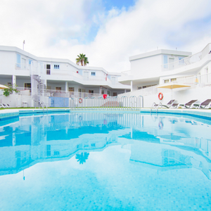 una gran piscina azul está rodeada de edificios blancos