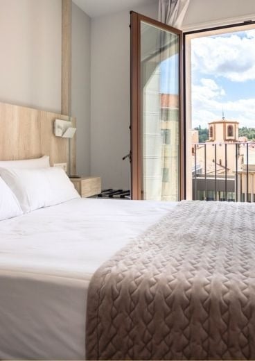 una habitación de hotel con una cama y una ventana abierta