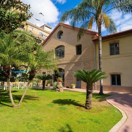 un gran edificio de ladrillo con palmeras en el patio