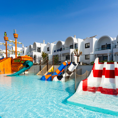 una piscina con toboganes y un barco pirata en el fondo